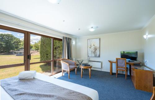 a hotel room with a bed and a desk and a table at Admirals Motor Inn in Nelson