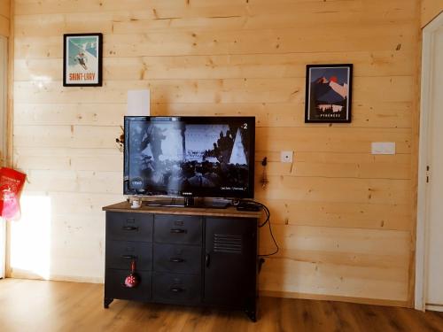 TV de pantalla plana en la parte superior de una pared de madera en Bel appartement proche Saint Lary Soulan, en Vielle-Aure