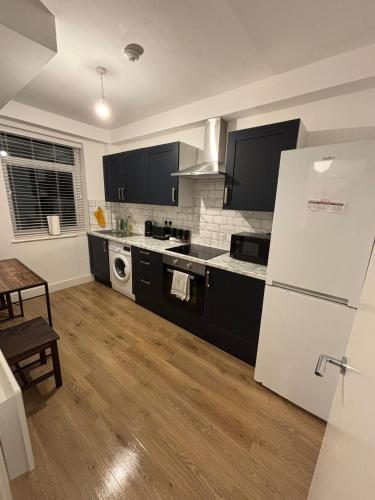 a kitchen with black cabinets and a white refrigerator at Beatiful 3 bedroom apartment near Tower Bridge in London