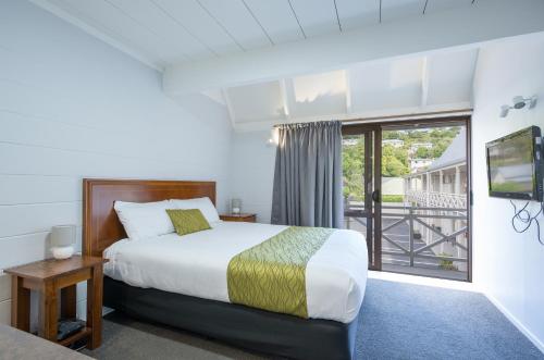 a bedroom with a bed and a large window at Admirals Motor Inn in Nelson
