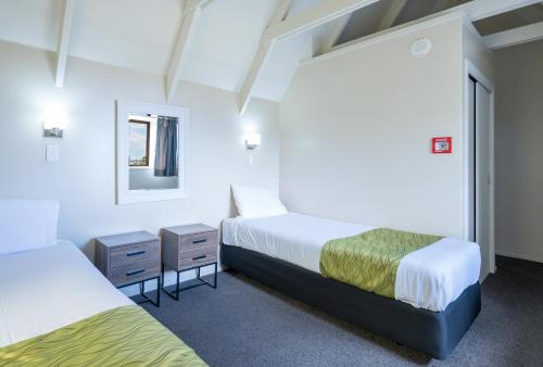a room with two beds and a mirror at Admirals Motor Inn in Nelson