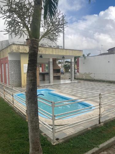a swimming pool in front of a building with a palm tree at Economize e aproveite a região ou descanse para o voo - 24h in Maceió