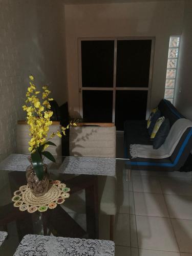 a living room with a vase of flowers on a table at Economize e aproveite a região ou descanse para o voo - 24h in Maceió