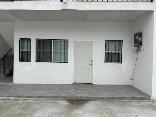a white wall with a door and two windows at Apartamentos la medero 4 in Nuevo Laredo