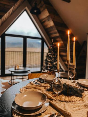 a table with plates and candles and a christmas tree at Okno w Gorce-magiczny apartament na uboczu nad jeziorem Czorsztyńskim, Velo Czorsztyn, Szczawnica, Zakopane in Maniowy