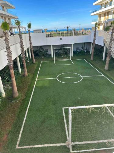 a tennis court in front of a building with palm trees at La perle du carrousel in Rabat