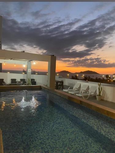 a swimming pool with chairs on the roof of a house at Condominio Mar y Arena in Mazatlán