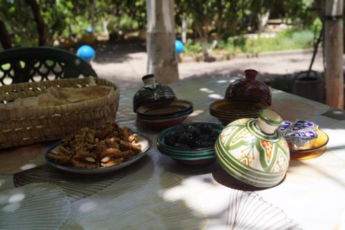 a table with vases and plates of food on it at Ferme d'hôtes Pouvoir des Plantes in Ourika
