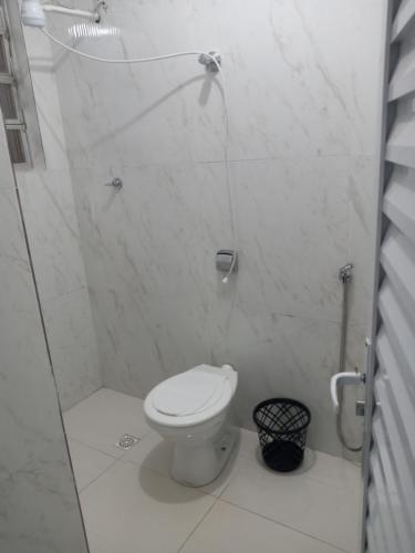 a white bathroom with a toilet and a shower at Casa com vista para o mar! in Peruíbe