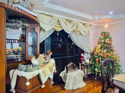 a christmas room with a christmas tree and a table at Apartamento espacioso y super cómodo Batan Shopping in Cuenca