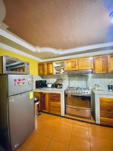 a kitchen with wooden cabinets and a stainless steel refrigerator at Apartamento espacioso y super cómodo Batan Shopping in Cuenca