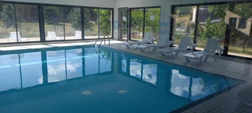 une grande piscine avec des chaises et des fenêtres dans l'établissement Appartement Soleil Neige Dévoluy grand confort, à Saint-Étienne-en-Dévoluy