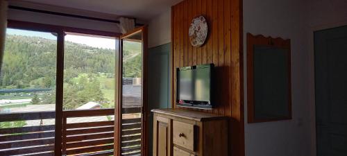 un salon avec une télévision et une grande fenêtre dans l'établissement Appartement Soleil Neige Dévoluy grand confort, à Saint-Étienne-en-Dévoluy