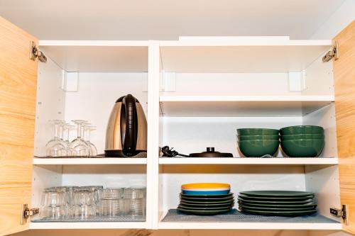 un garde-manger avec assiettes et bols sur étagères dans l'établissement Qhome 8 - T2 Cosy entre Paris & Disney, à Noisy-le-Grand