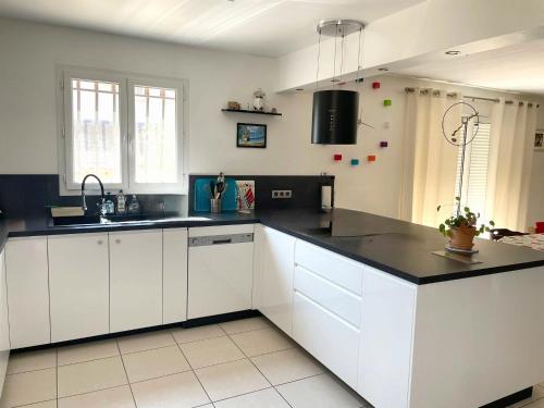 une cuisine avec des armoires blanches et des comptoirs noirs dans l'établissement Charmante maison à 5 minutes du Pont du Gard, à Vers-Pont-du-Gard