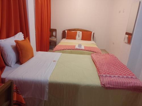 two beds in a small room with orange curtains at Hotel Chachapoyas in Chachapoyas