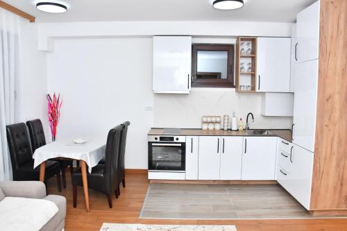 a kitchen with white cabinets and a table and chairs at Apartman Kragujevac in Kragujevac