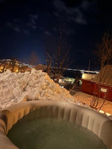a hot tub covered in snow at night at Tromso budget apartement in Tromsø