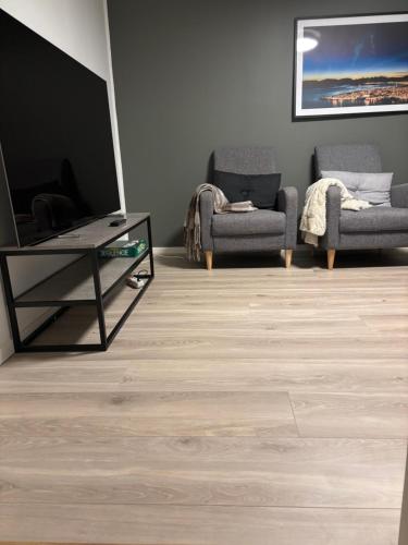 a living room with a tv and two chairs and a table at Tromso budget apartement in Tromsø