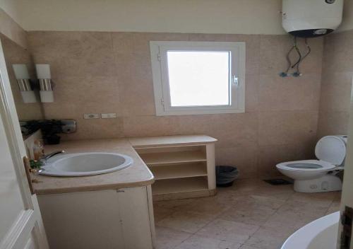 a bathroom with a sink and a toilet and a window at Stylish 4 BR with a Private Heated Pool V15 at White Villas in Hurghada