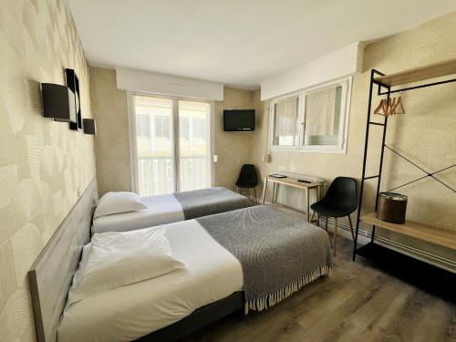 a hotel room with two beds and a table and chairs at Hôtel Le Littoral - Berck sur Mer in Berck-sur-Mer