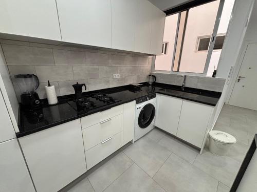 een keuken met witte kasten en een wasmachine bij Urban Mindelo in Mindelo