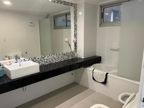 ein weißes Badezimmer mit Waschbecken und Spiegel in der Unterkunft Amplio con vista al mar in Balneario Monte Hermosa