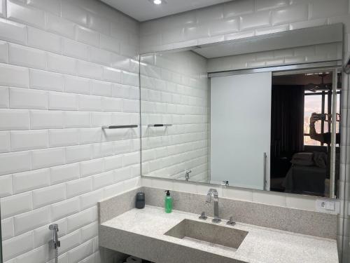 a bathroom with a sink and a large mirror at Flat Residence Campinas in Campinas