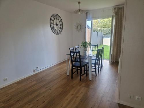 une salle à manger avec une table, des chaises et une horloge murale dans l'établissement Charming Home, à Hérouville-Saint-Clair