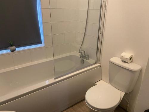 a bathroom with a toilet and a bath tub with a window at Spacious 4 Bedroom Townhouse in Leeds