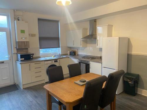 a kitchen with a table and chairs and a refrigerator at Spacious 4 Bedroom Townhouse in Leeds