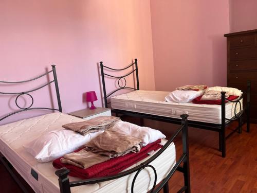 two twin beds in a room with pink walls at Giora House in Capracotta