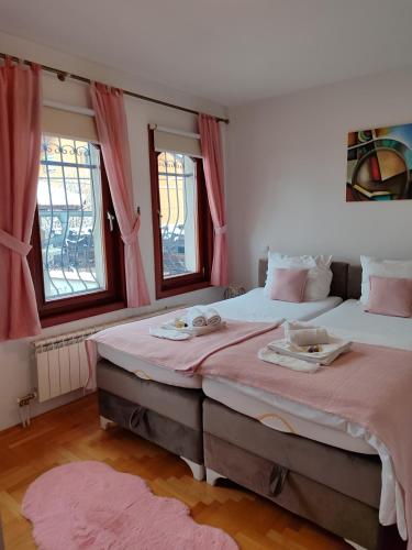 two beds in a room with pink curtains at Villa Kuna in Sarajevo