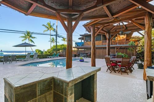een patio met een tafel en stoelen en een zwembad bij Seaside Retreat Condo in Kailua-Kona