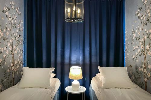 two beds in a room with blue curtains and a lamp at Hangon Herttua Apartment in Hanko in Hanko