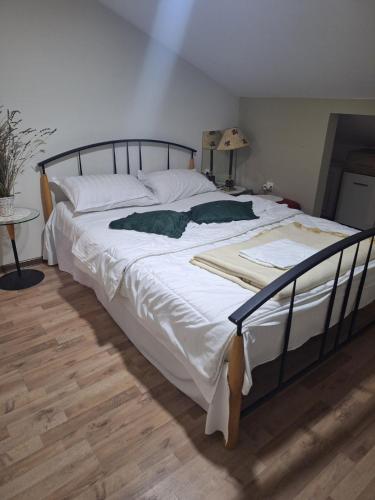 a large bed with white sheets and green pillows at Jezero in Arandjelovac