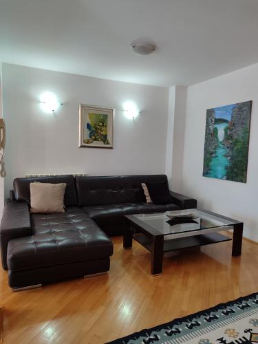 a living room with a black leather couch and a coffee table at Villa Kuna in Sarajevo