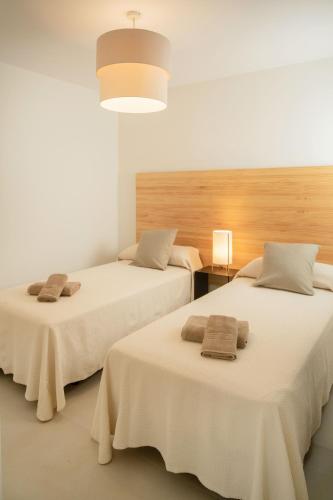 two beds in a room with white walls at Flora - Panasco Suites in Arrecife