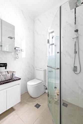 a bathroom with a toilet and a glass shower at Double Room in Kingsford - Next to the Station - Shared Bathroom in Sydney