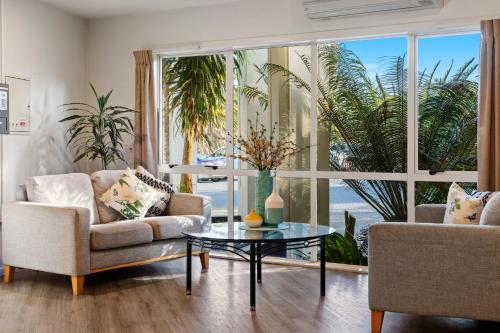 a living room with two couches and a glass table at Taipa Beach Resort in Taipa