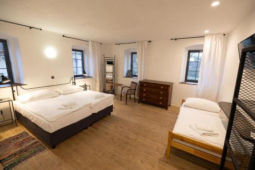a bedroom with two beds and a dresser and windows at Horní Strakův mlýn in Úštěk