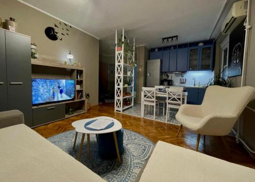 a living room with a couch and a table and a kitchen at Apartman Avenia in Novi Sad