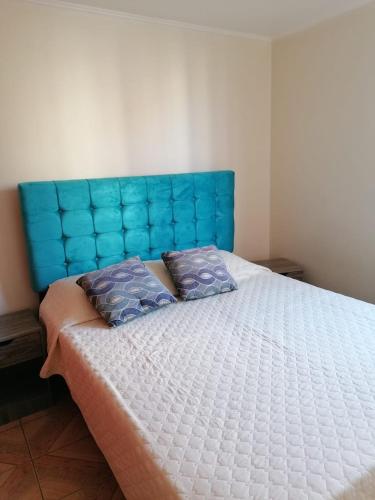 a bed with a blue headboard in a bedroom at D12-E15 Amoblado y equipado a pasos de la playa Arica in Arica