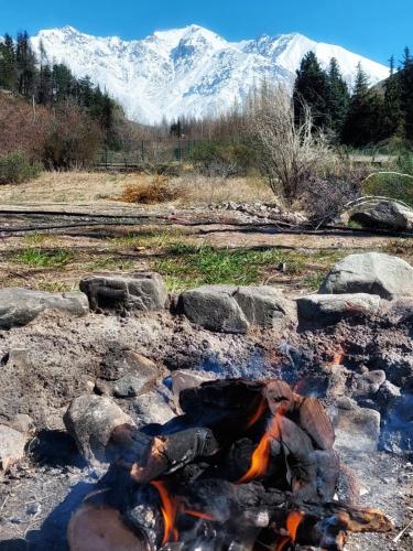 a fire pit with rocks and mountains in the background at Cabaña en potrerillos con bajada al arroyo in Potrerillos