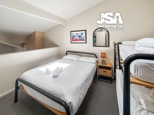 a small bedroom with two beds and a mirror at Razorback 2 in Jindabyne