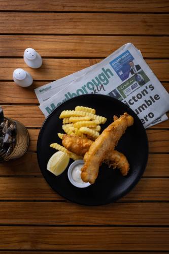 a plate of food with fish and french fries and a newspaper at Edit Picton in Picton