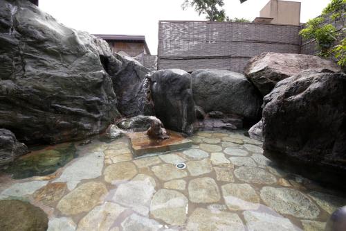 a pool of water with rocks and a fountain at Sekitaitei Ishida in Achi