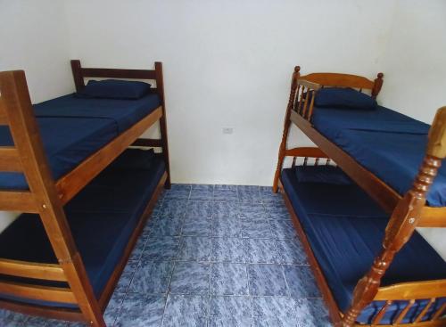 two bunk beds in a room with blue sheets at Hostel 5C - Itanhaém in Itanhaém