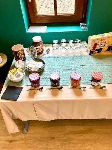 a table with a white table cloth with jars of food at Résidence Normandie in Conches-en-Ouche