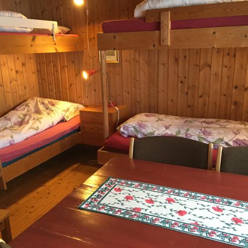 a room with two beds and a table with a rug at Putten Seter in Høvringen